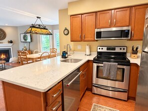 A kitchen with wooden cabinets, a stainless steel microwave, an oven, and a granite countertop. - SnowDen- Ski on Ski Off at Pico, FirePlace, Pool! (Killington)