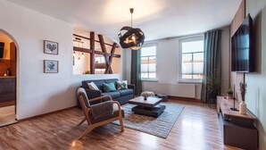 Una sala de estar moderna con piso de madera, un sofá, una mesa de centro y un televisor montado en la pared.