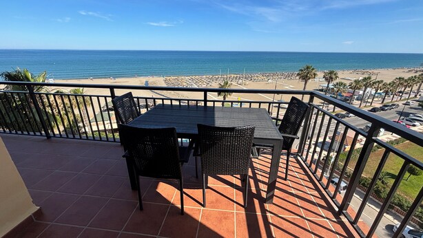 Un balcón con mesa y sillas con vista a la playa.