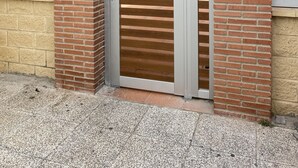 Entrada de un edificio con una puerta numerada, un buzón y un letrero de una tienda de fotografía.