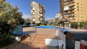Zona de piscina con escalones de acceso, rodeada de edificios de apartamentos.