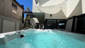 Una piscina amb tapa blanca, envoltada d'un edifici modern i un cel blau clar.