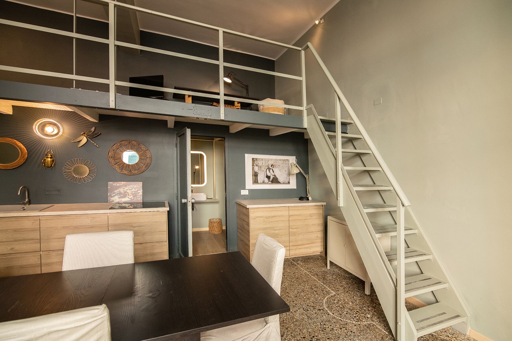 Un dormitorio estilo loft con una cama litera, un escritorio y una escalera.