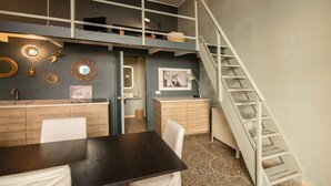 Un dormitorio estilo loft con una cama litera, un escritorio y una escalera.