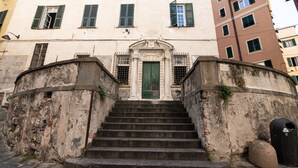 Un edificio con una entrada central, una puerta verde y una escalera que lleva a ella.