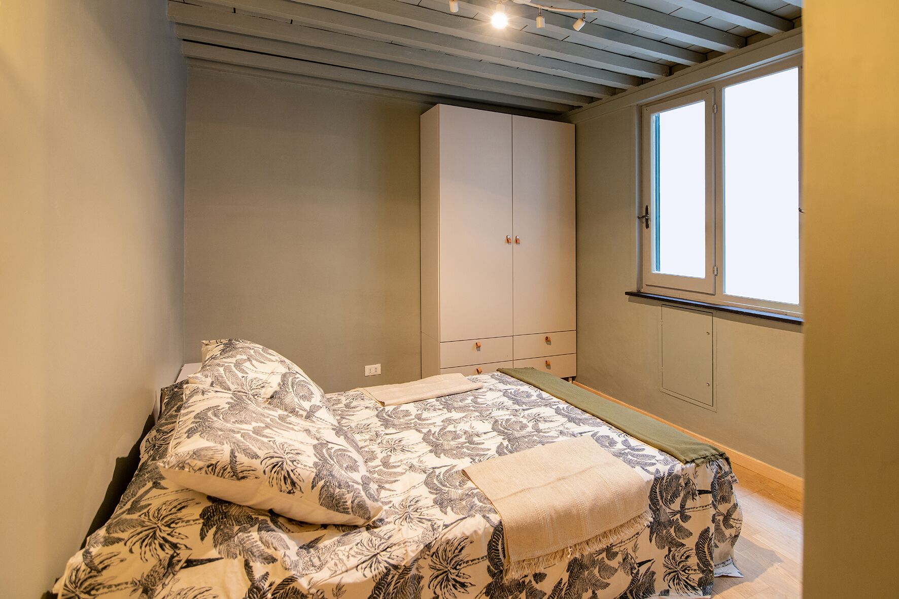Une chambre à coucher avec un lit, une armoire et une fenêtre.
