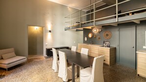 Una cocina moderna con zona de comedor, que incluye una mesa de madera oscura, sillas blancas y un banco empotrado.