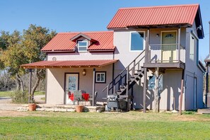 Ein zweistöckiges Haus mit rotem Dach, einer Veranda und einer Treppe, die zum oberen Stockwerk führt.