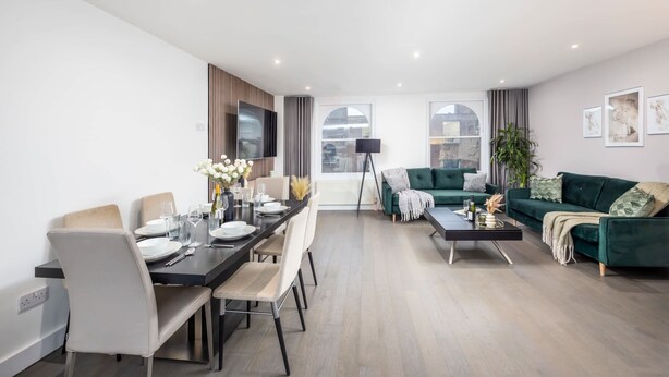 Un salon moderne comprenant un coin repas, un canapé vert et une table basse noire.