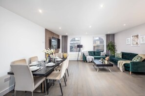 A modern living room with a dining area, a green sofa, and a black coffee table.