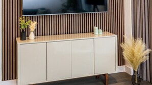 Un salon moderne doté d’un grand téléviseur à écran plat fixé au mur, lequel est recouvert de lambris en bois verticaux.