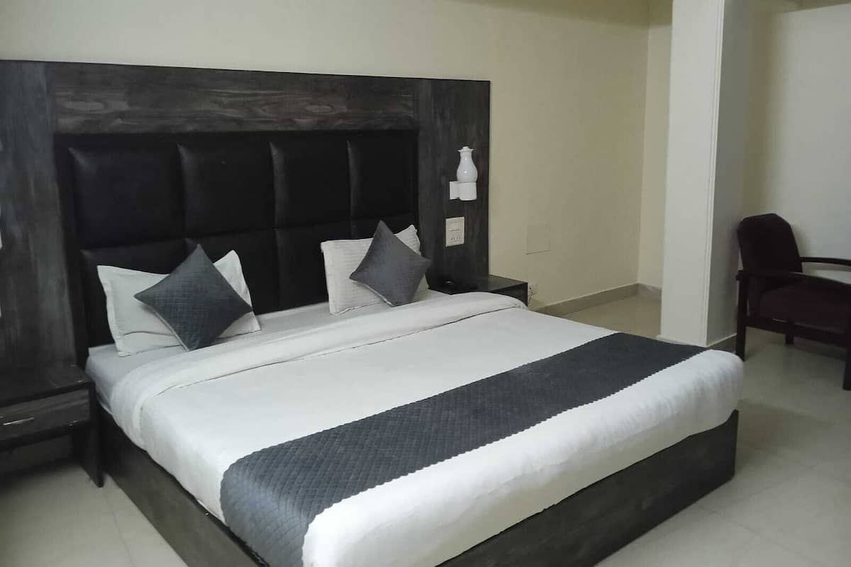 Una cama bien hecha con un cabecero oscuro, ropa de cama blanca y dos almohadas.