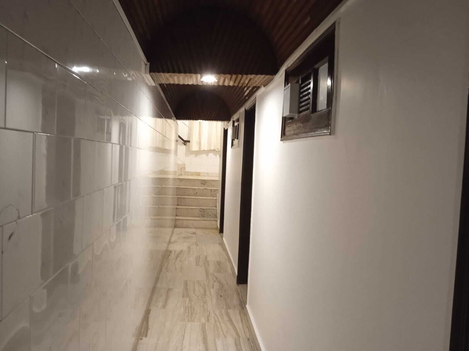 A hallway with tiled walls, a wooden ceiling, and a staircase leading to another room.