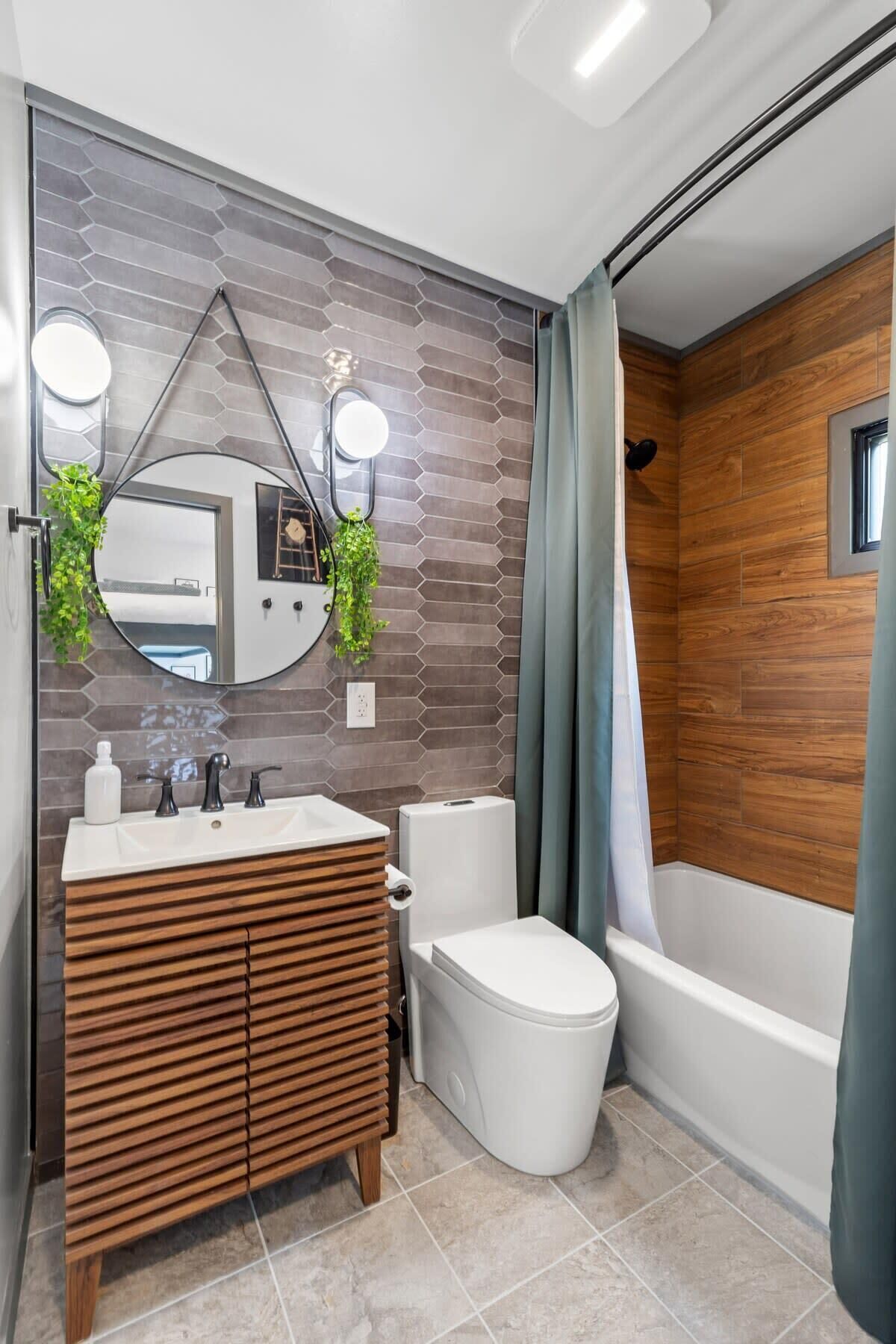 Un baño moderno con un mueble de tocador de madera, un inodoro blanco y una bañera.