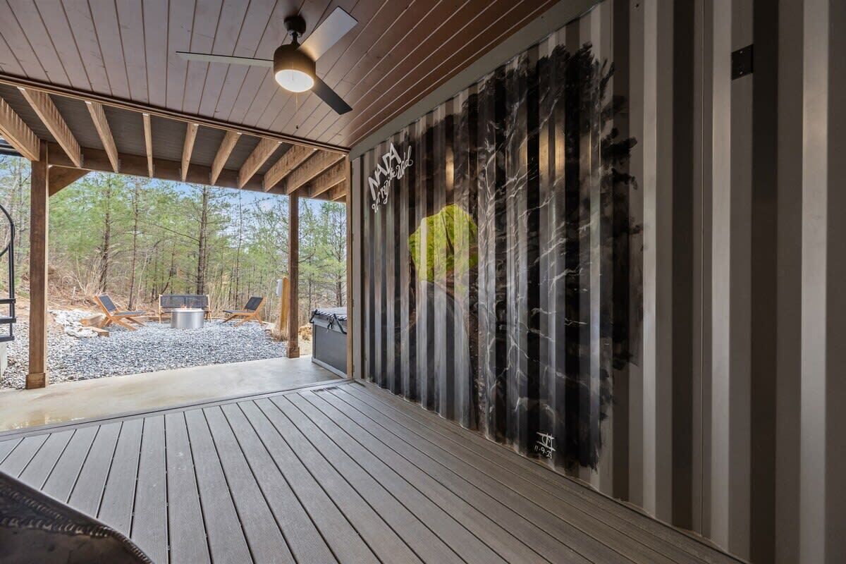 A covered outdoor area with a wooden deck, a ceiling fan, and a fire pit.