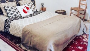 Quarto com cama, mesa de cabeceira, cadeira e espelho na parede.