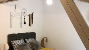 Quarto com cama, mesa de cabeceira, abajur e decorações nas paredes.