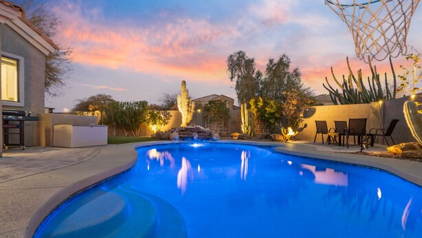 A swimming pool with a curved edge, surrounded by cacti and desert plants, with a basketball hoop on the right. - 3BD - Heated Pool - Pet friendly - N. Scottsdale (Cave Creek)