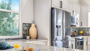 A modern kitchen with stainless steel appliances, a large window, and a decorative vase. - 3BD - Heated Pool - Pet friendly - N. Scottsdale (Cave Creek)