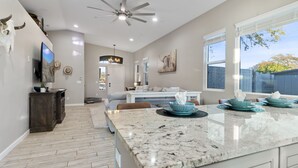 A spacious kitchen with a marble countertop, a ceiling fan, and a large window with a view of the outdoors. - 3BD - Heated Pool - Pet friendly - N. Scottsdale (Cave Creek)