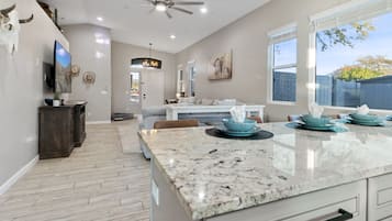 A spacious kitchen with a marble countertop, a ceiling fan, and a large window with a view of the outdoors.