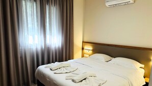 Een hotelkamer met een bed, gordijnen, een airconditioning en een bedlamp.