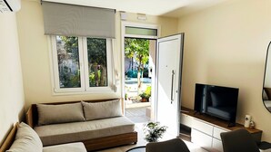 Een moderne woonkamer met een bank, televisie, eettafel en uitzicht op de omgeving.