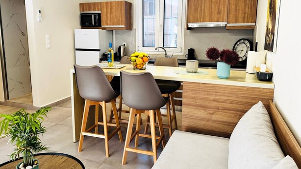 Een moderne keuken met houten kastjes, een magnetron en een eethoek met krukken.