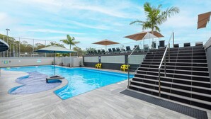 A swimming pool with steps leading down to the water, surrounded by lounge chairs and umbrellas. - The Landmark unit 405 Resort style, spectacular water views, lift, linen, pool, games room, port-a-cot and highchair. (Nelson Bay)