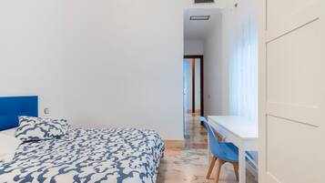 Un dormitorio con una cama, un escritorio y una silla.