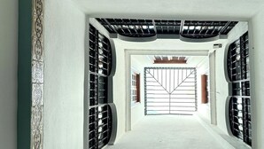 Vista de uma varanda com janela central, cercada por grades de metal preto e uma borda decorativa.