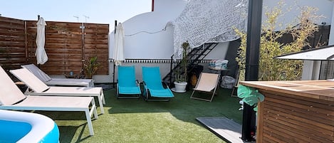 Un área de piscina con sillones de descanso, una piscina inflable pequeña y una terraza de madera.