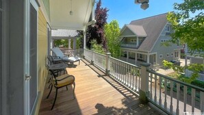 A wooden deck with outdoor furniture, a railing, and a view of neighboring houses.