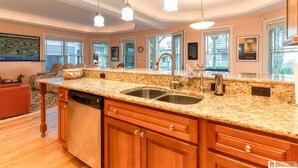 A spacious kitchen with granite countertops, wooden cabinets, and pendant lighting.