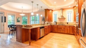 A spacious kitchen with wooden cabinets, a granite countertop, and a stainless steel refrigerator.