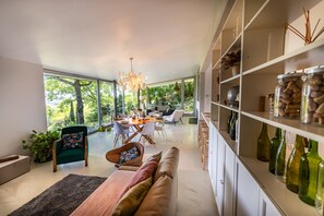 Un interior moderno con comedor, sofá y estanterías llenas de botellas.