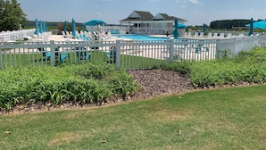 A pool area with a white fence, lounge chairs, and umbrellas. - Kelly's Cozy Golf Getaway/ Enclosed Patio/ Lakeside/Woodlake's Maples Golf Course on Site/Minutes from Fort Bragg/40 Plus Golf Courses Nearby/Sleeps 8 (Vass)