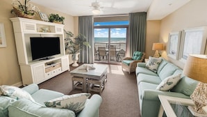 A living room with a TV, sofa, and a balcony with a view of the ocean. - Luxurious Oceanfront 2 Bdrm Condo Stunning Views (North Myrtle Beach)