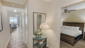 A hotel hallway with a bed, a console table with a lamp, and a view of the ocean. - Luxurious Oceanfront 2 Bdrm Condo Stunning Views (North Myrtle Beach)