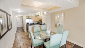 A modern kitchen with a central island, light blue chairs, and a glass dining table. - Luxurious Oceanfront 2 Bdrm Condo Stunning Views (North Myrtle Beach)