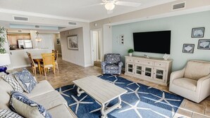 Un salon comprenant un canapé, une table basse et des fauteuils, un coin repas avec une table et des chaises, un téléviseur et un meuble.