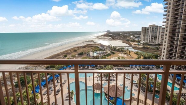 Un resort con vista a la playa, varias piscinas y un edificio de gran altura.