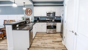 Una cocina moderna con armarios blancos, electrodomésticos de acero inoxidable y piso de madera.