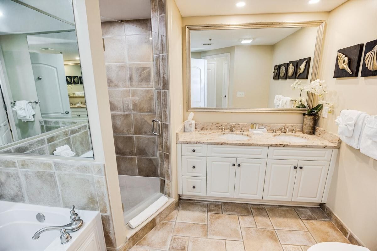 A bathroom with a bathtub, a shower, a sink with a large mirror, and a toilet.