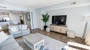 A modern living room with a grey sofa, a coffee table, and a TV on a wooden cabinet. - Relax in Style: Oceanfront 3 Bedroom Condo (North Myrtle Beach)