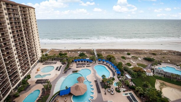 Ein Hotel mit mehreren Schwimmbecken, einem Strand und Blick aufs Meer.