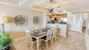 A dining area with a wooden table and chairs, a chandelier, and decorative wall art. - Seaside Perfection 3 Bdrm Oceanfront w/ Whirlpool (North Myrtle Beach)