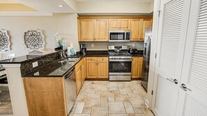 A kitchen with wooden cabinets, a granite countertop, a stainless steel oven, and a microwave. - Seaside Perfection 3 Bdrm Oceanfront w/ Whirlpool (North Myrtle Beach)