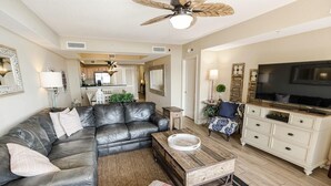A living room with a sectional sofa, a coffee table, a TV, and a ceiling fan. - Seaside Perfection 3 Bdrm Oceanfront w/ Whirlpool (North Myrtle Beach)
