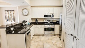 A kitchen with white cabinets, a microwave, an oven, and a coffee maker.